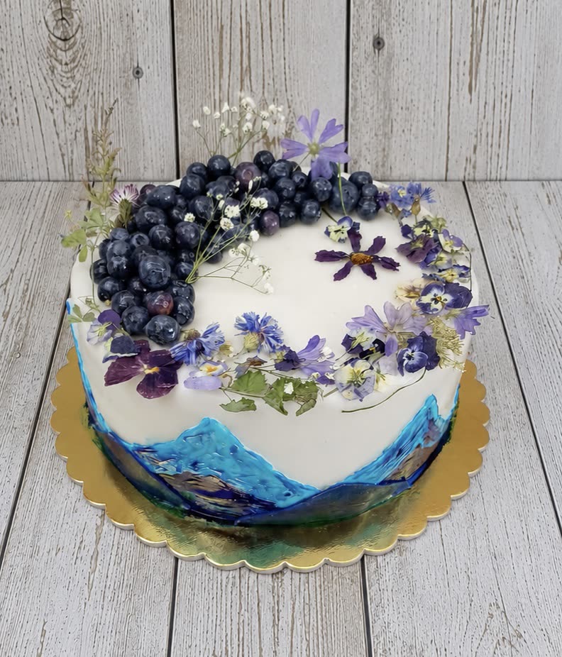 Fehér torta préselt lila virágokkal, áfonyával és festett kék mintával