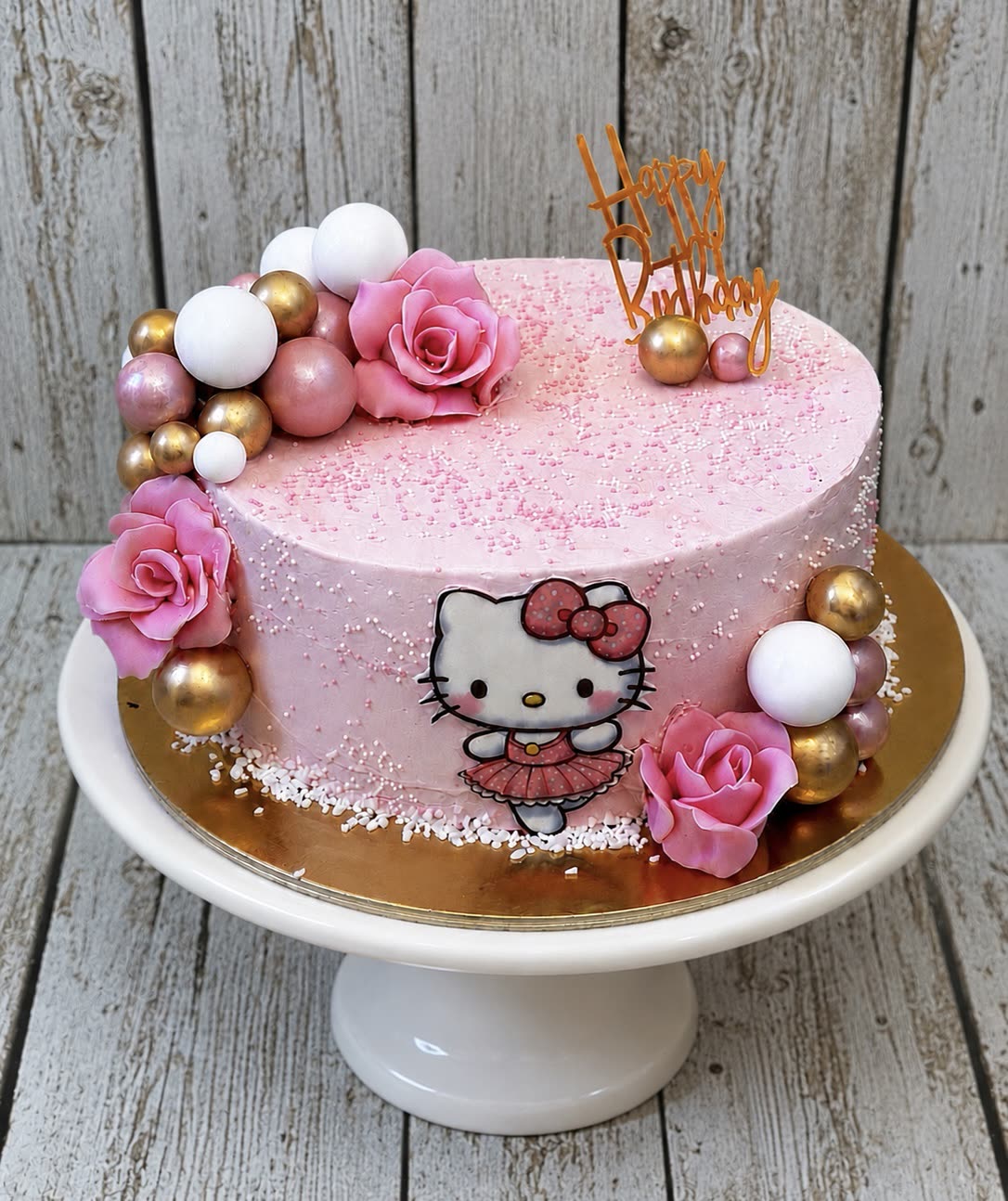 Rózsaszín Hello Kitty torta cukorrózsákkal és arany gömbökkel
