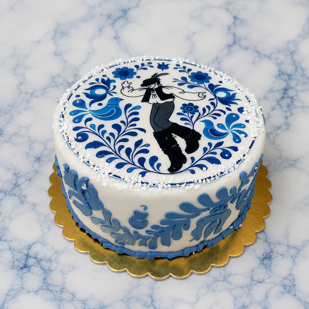 Fehér torta kék népi mintákkal és néptáncos alakkal