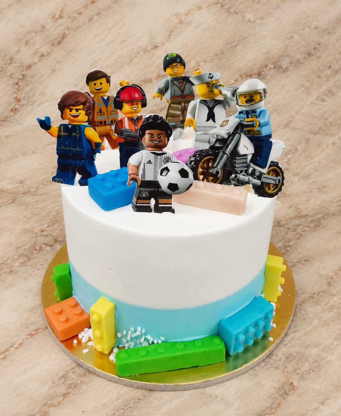 Fehér-kék LEGO torta minifigurákkal és színes kockákkal