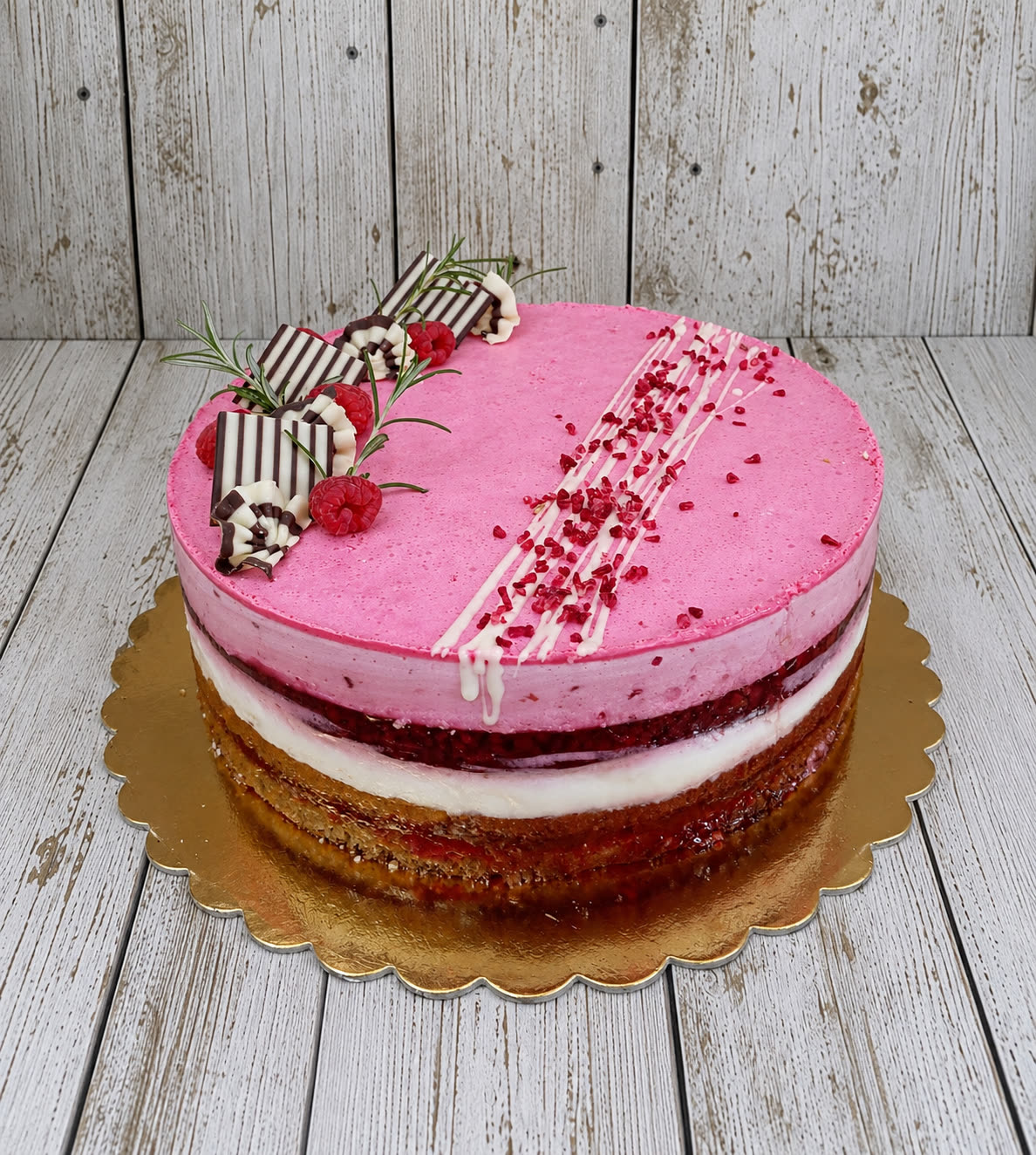 Rózsaszín málnás torta fehércsokoládé díszekkel