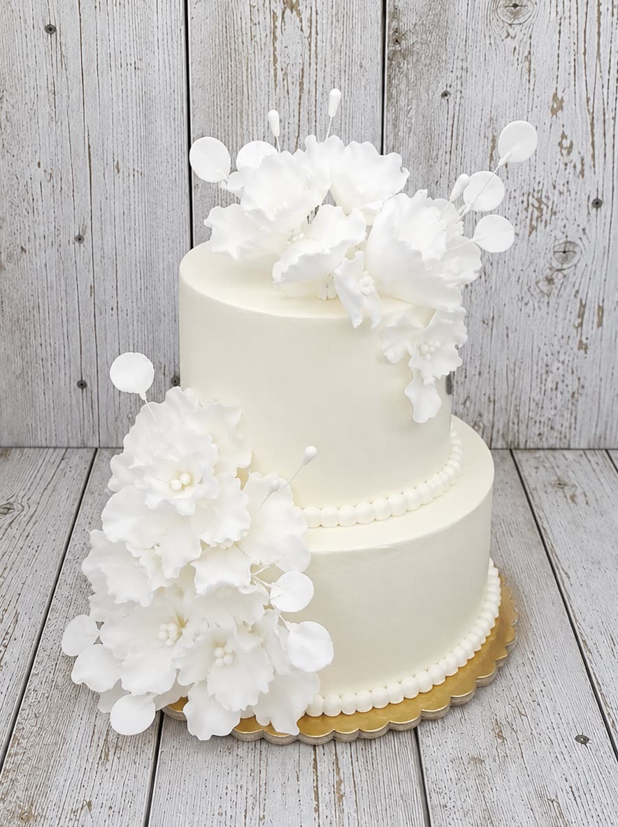 Kétemeletes krémszínű torta fehér ostyavirágokkal